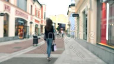 一个穿着高跟鞋、带着购物袋走着走着的模糊的、苗条的黑发女孩。 4Kboke背景视频